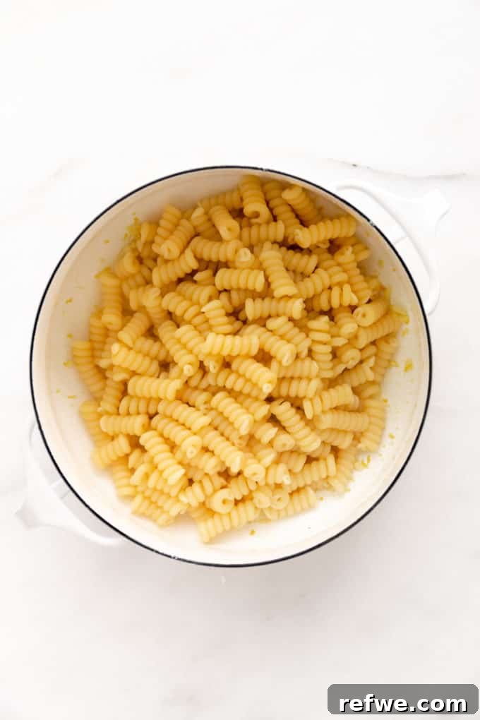 Zesty Lemon Garlic Pasta 5 Al dente fusilli noodles cooking in a white pot of boiling water, ready to be drained