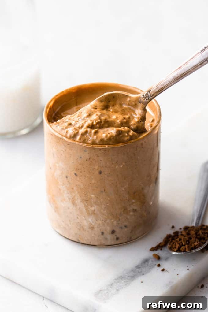 Java Overnight Oats 11 A spoon scooping a generous portion of creamy coffee overnight oats out of a cup, highlighting its ready-to-eat texture.