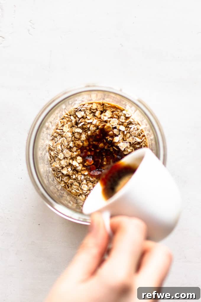 Java Overnight Oats 5 A stream of rich coffee being poured into a cup containing dry oats, beginning the mixture for overnight oats.