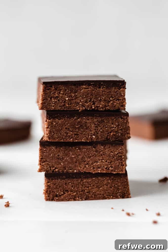 Effortless Fudgy Chocolate Protein Bars 2 Four chocolate protein bars stacked neatly, showcasing their rich chocolate topping and inviting texture.
