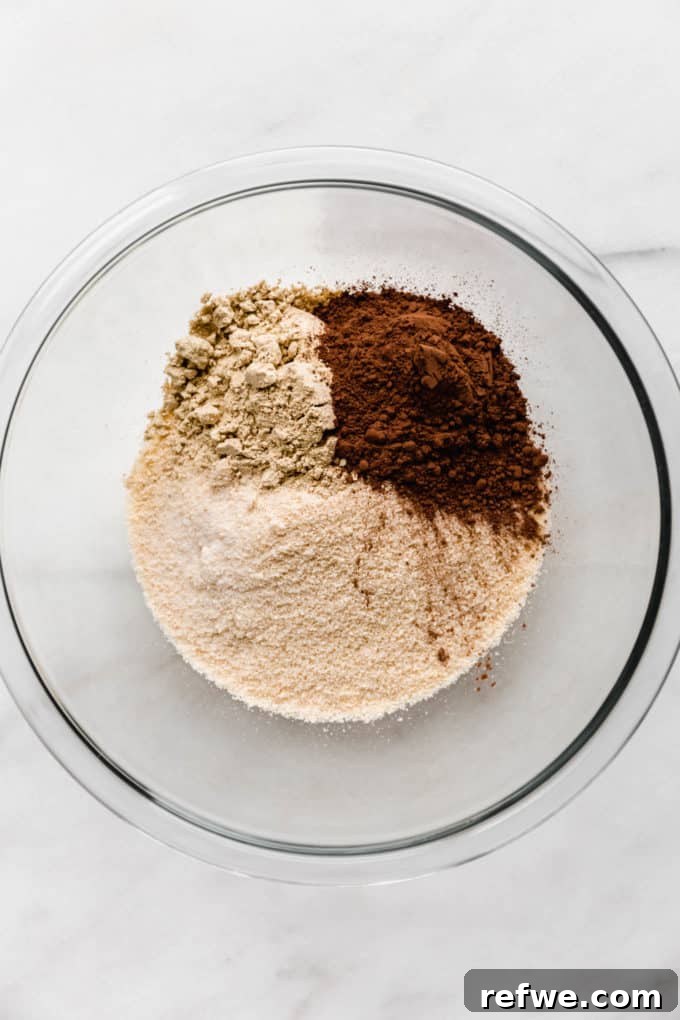 Effortless Fudgy Chocolate Protein Bars 4 Almond flour, cocoa powder, and protein powder meticulously measured and blended in a mixing bowl, ready for the next step.