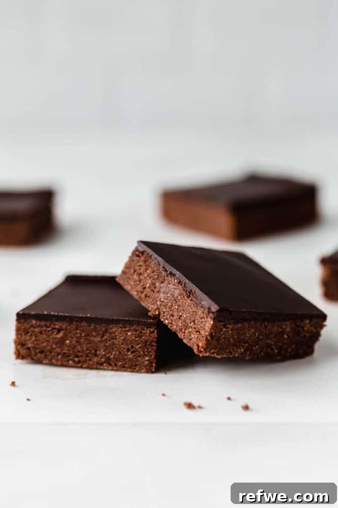 Effortless Fudgy Chocolate Protein Bars 10 Two perfectly cut chocolate protein bars resting on parchment paper, ready to be enjoyed.