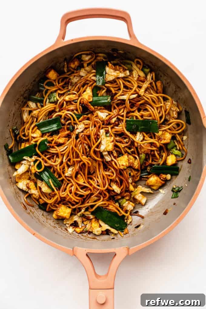 Indonesian Fried Noodles Mie Goreng 13 Mie Goreng fully mixed and sizzling in a pink pan, coated in the stir-fry sauce.