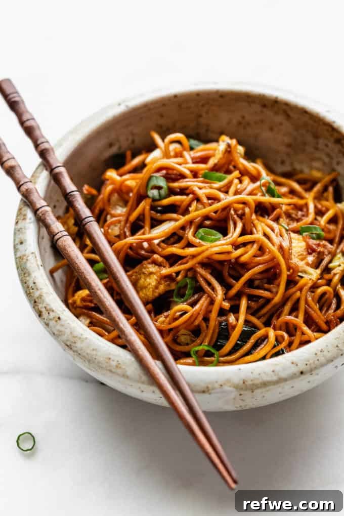 Indonesian Fried Noodles Mie Goreng 16 Mie Goreng noodles served in a white speckled bowl, garnished with green onions.
