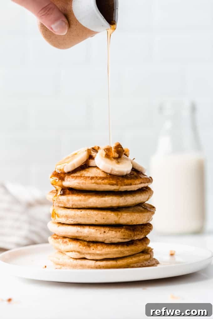 Wholesome Oat Flapjack Feast 11 Rich maple syrup being drizzled over a tall stack of warm oat flour pancakes