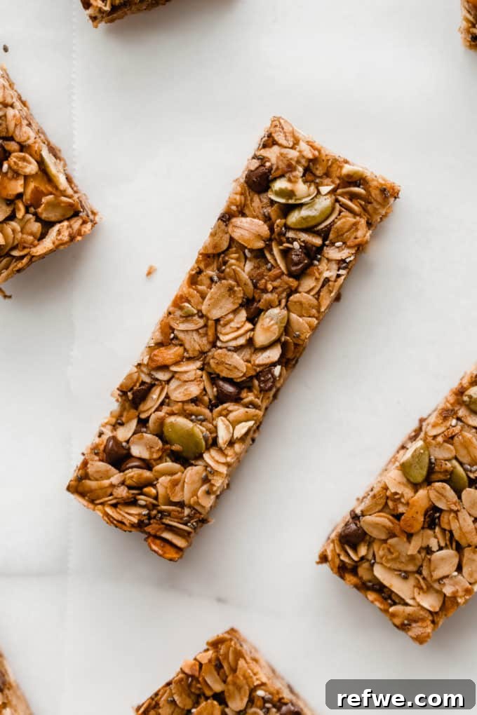 Wholesome Energy Muesli Bars 2 A perfectly baked muesli bar resting on parchment paper, showcasing its rich texture with visible oats, nuts, and seeds.