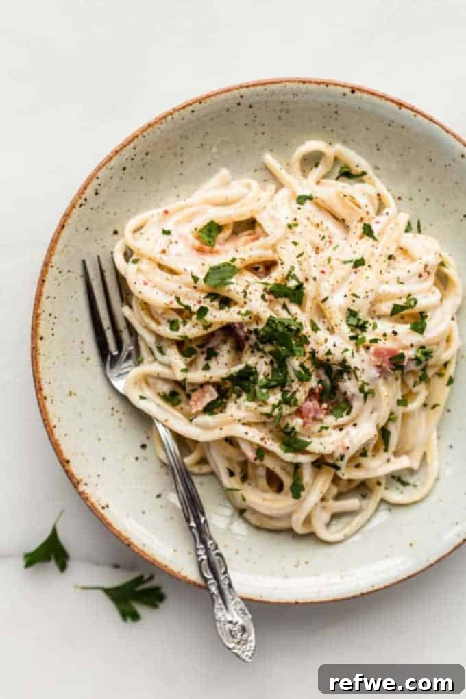 31 Irresistible Vegan Pasta Dishes 10 A plate of flavorful vegan carbonara spaghetti, served in a white speckled plate with a fork poised to enjoy.