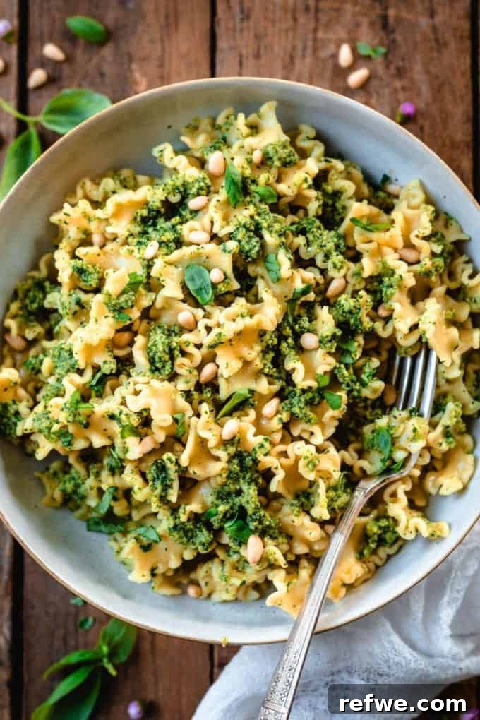31 Irresistible Vegan Pasta Dishes 12 Vibrant pasta with fresh green pesto, beautifully presented in a bowl on a rustic wood table.