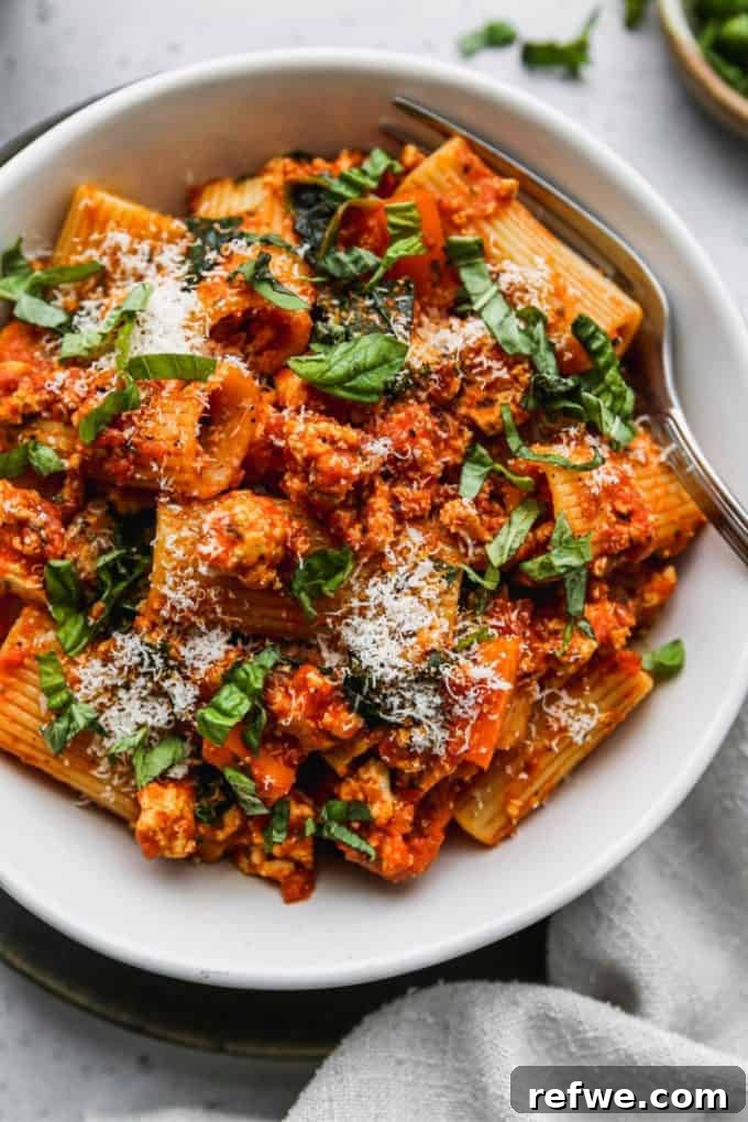 31 Irresistible Vegan Pasta Dishes 21 Rigatoni pasta mixed with crumbled tofu and a vibrant tomato sauce, served in a clean white bowl.