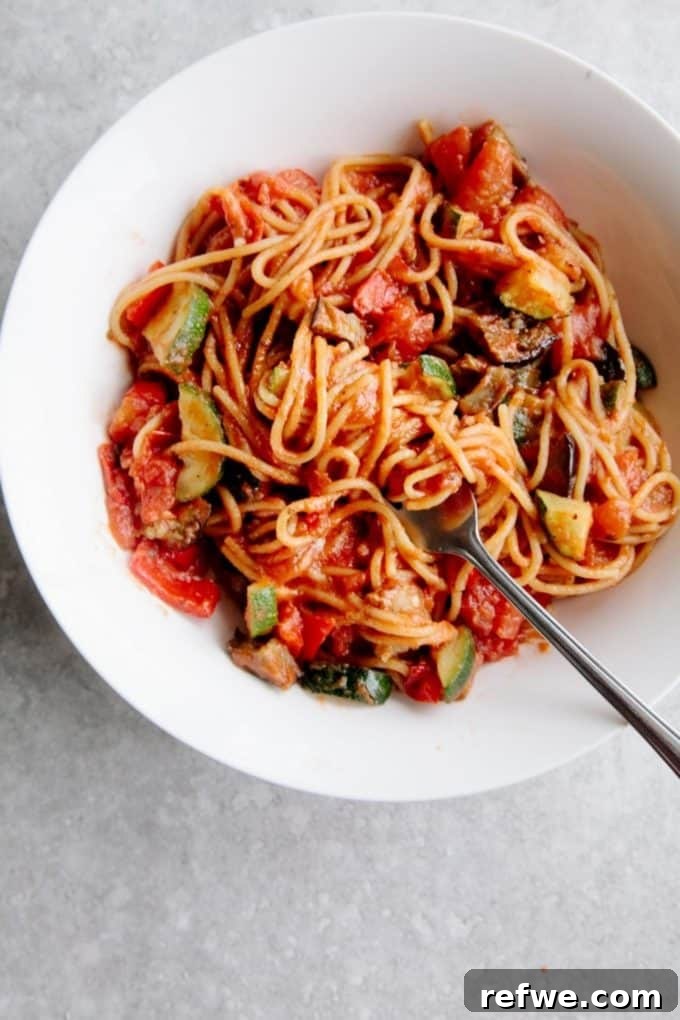 31 Irresistible Vegan Pasta Dishes 4 Spaghetti tossed with a rich tomato sauce and a medley of colorful vegetables, served in a white bowl.