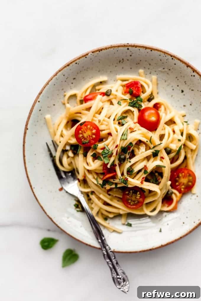 31 Irresistible Vegan Pasta Dishes 3 Delicious linguine pasta mixed with vibrant cherry tomatoes and fresh basil, served on a white ceramic plate.