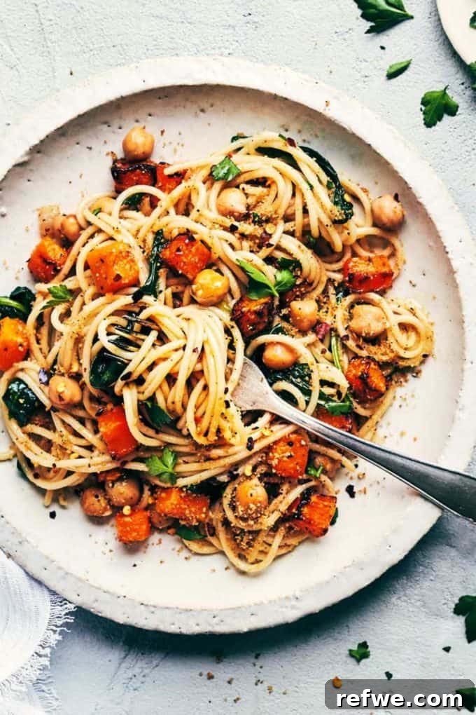 31 Irresistible Vegan Pasta Dishes 23 Spaghetti generously topped with roasted butternut squash, chickpeas, and fresh herbs on a white plate.