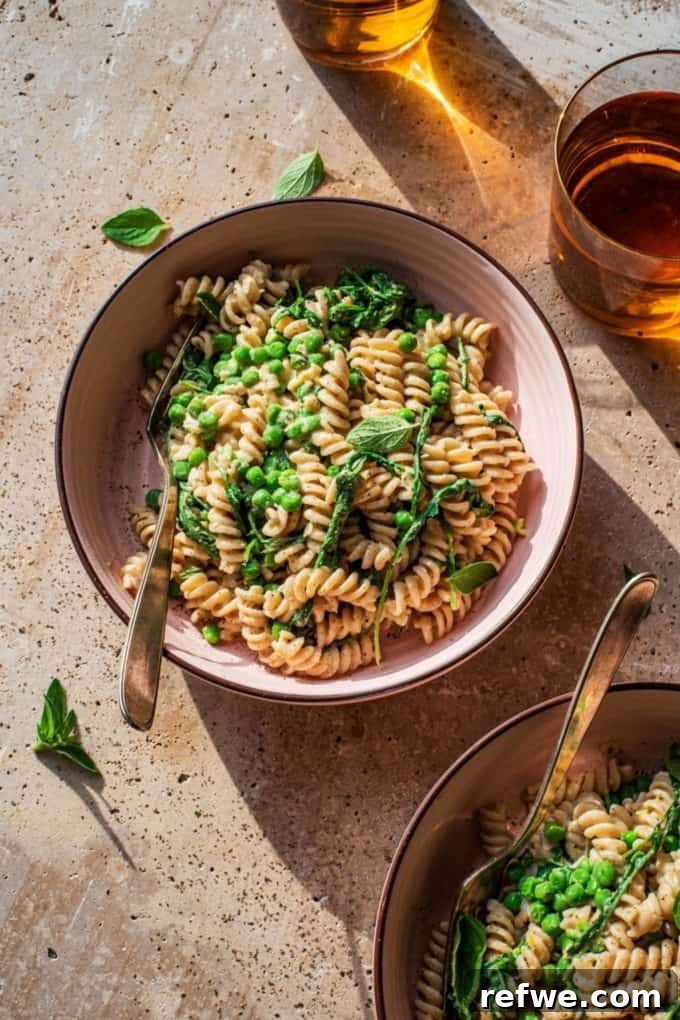 31 Irresistible Vegan Pasta Dishes 17 Two enticing bowls of fusilli pasta, generously mixed with vibrant green peas and fresh basil.