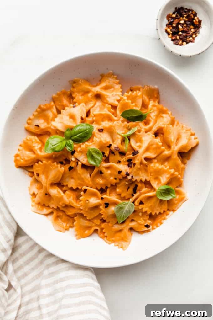 31 Irresistible Vegan Pasta Dishes 6 A delectable bowl of creamy vegan vodka pasta, garnished with fresh basil, with a sprinkle of chili flakes on the side.