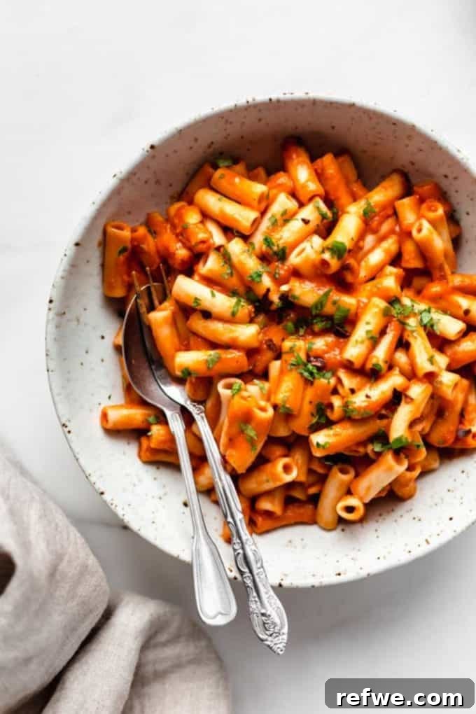 31 Irresistible Vegan Pasta Dishes 19 Rich and creamy roasted red pepper pasta, served in a white speckled bowl with a fork and spoon.