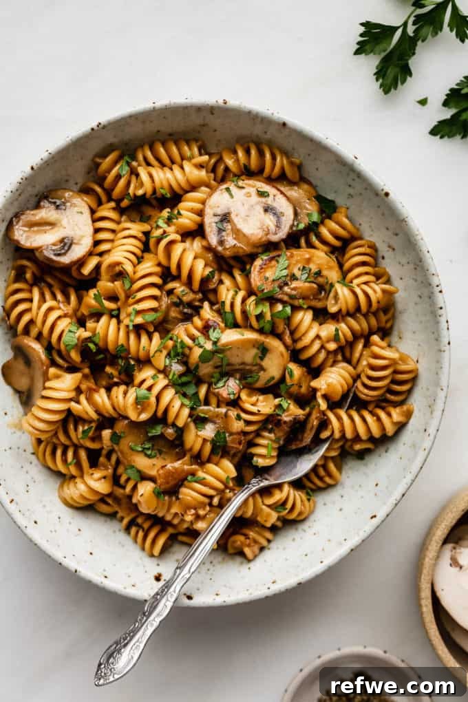 31 Irresistible Vegan Pasta Dishes 8 A savory bowl of one-pot vegan mushroom stroganoff, complete with a fork, ready to be enjoyed.