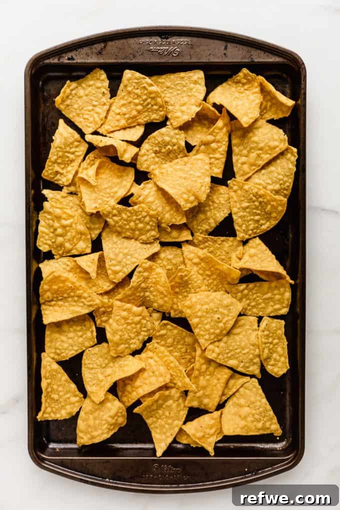 Irresistible Vegetarian Nachos 3 Tortilla chips evenly spread on a baking sheet, forming the base layer for nachos.