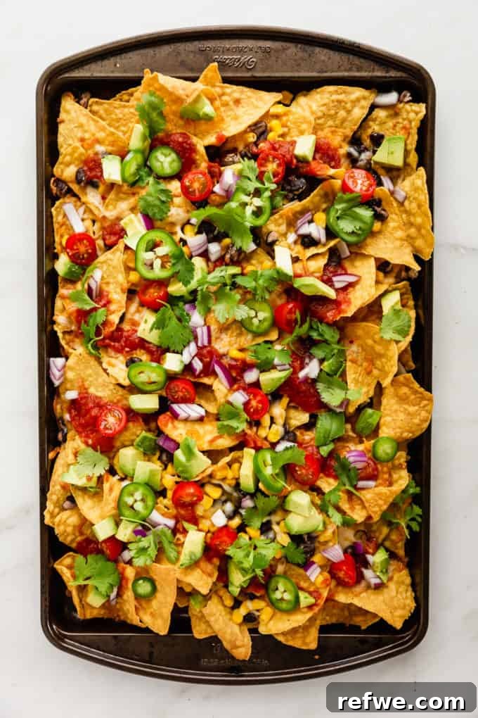 Irresistible Vegetarian Nachos 7 A large baking sheet filled with fully assembled vegetarian nachos, topped with all fresh ingredients.