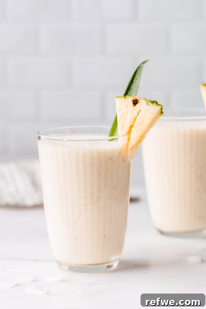 Pina Colada Dream Smoothie 6 Two beautifully presented glasses of Pina Colada Smoothie, garnished and ready to be enjoyed on a marble countertop.