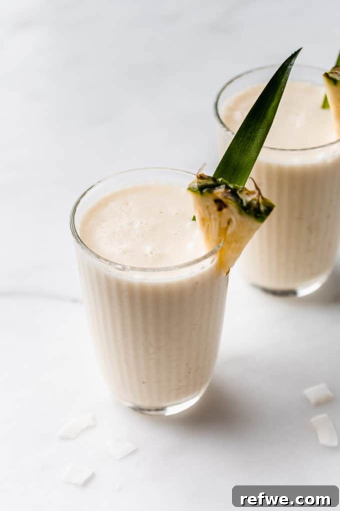 Pina Colada Dream Smoothie 7 A beautifully garnished Pina Colada Smoothie in a glass, with a fresh pineapple slice on the rim, ready for enjoyment.