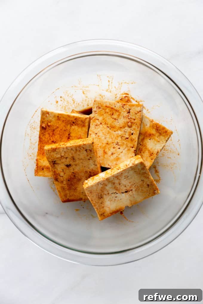 Squares of tofu fully coated in a vibrant marinade, soaking up the flavors.
