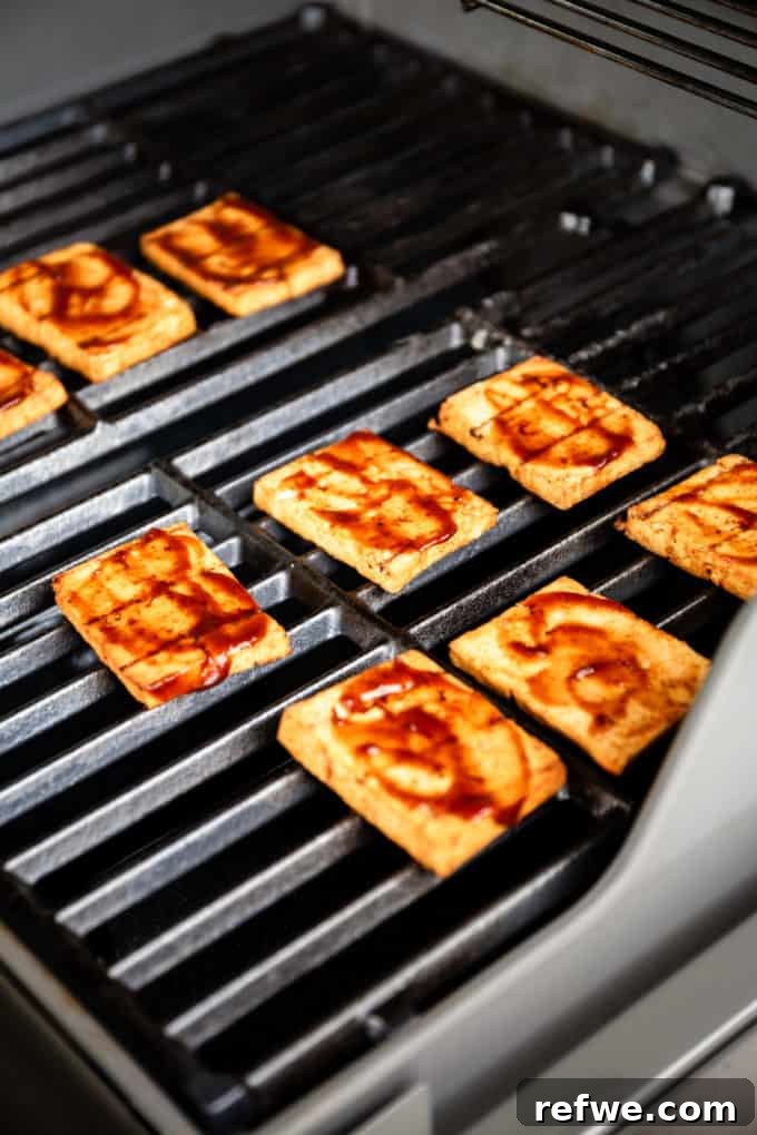 Grilled tofu coated with barbecue sauce, sizzling on the grates.