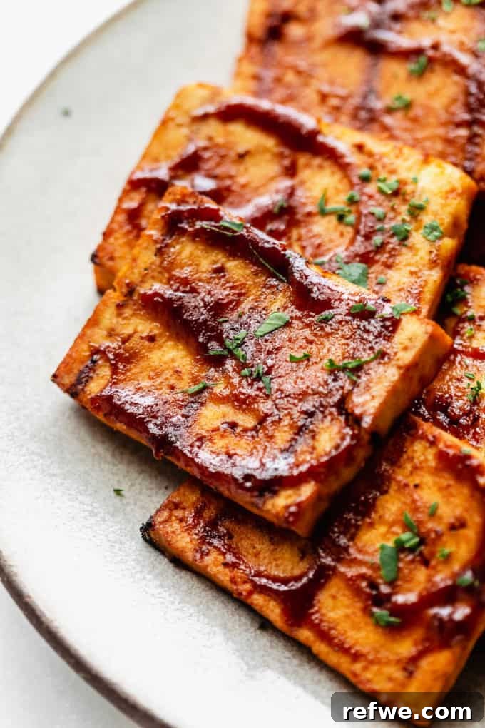 A close-up shot of a piece of barbecue tofu, showcasing its charred exterior and juicy interior.