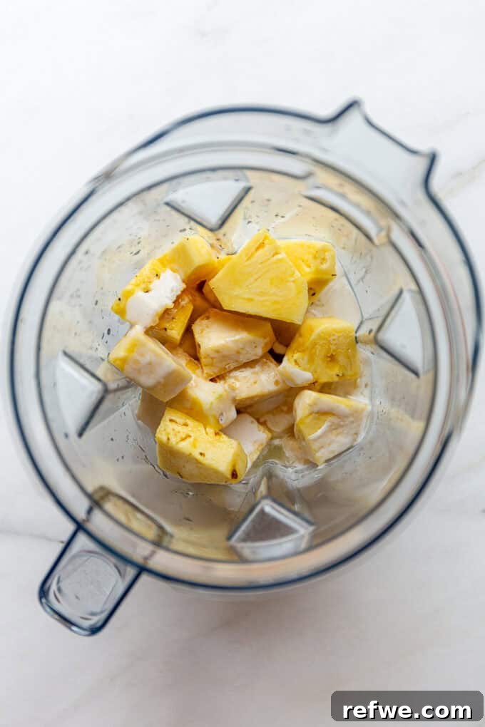 Paradise Pina Colada Pops 4 Pineapple and coconut milk being added to a blender for the popsicle base.