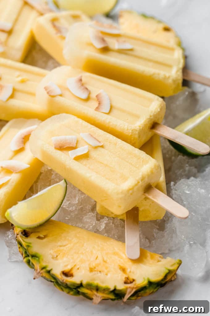 Paradise Pina Colada Pops 7 Close-up of finished Pina Colada popsicles on ice, garnished with coconut flakes, ready to be eaten.