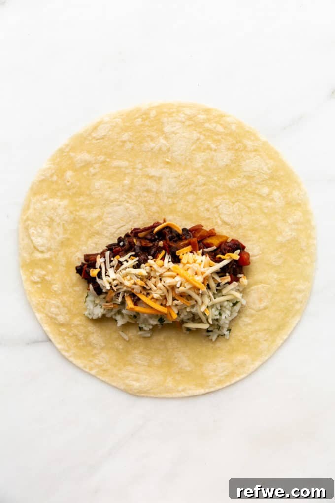 A tortilla generously filled with vibrant cilantro lime rice, spicy black beans, and shredded cheese, strategically placed for optimal rolling.