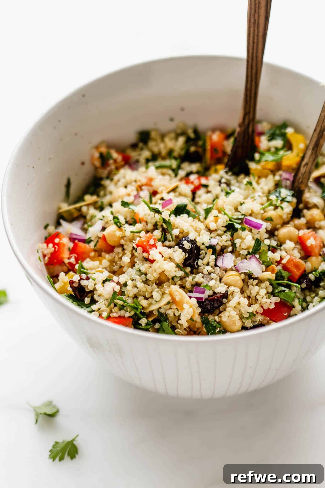 Quinoa chickpea salad in a salad bowl, garnished with fresh herbs and almonds