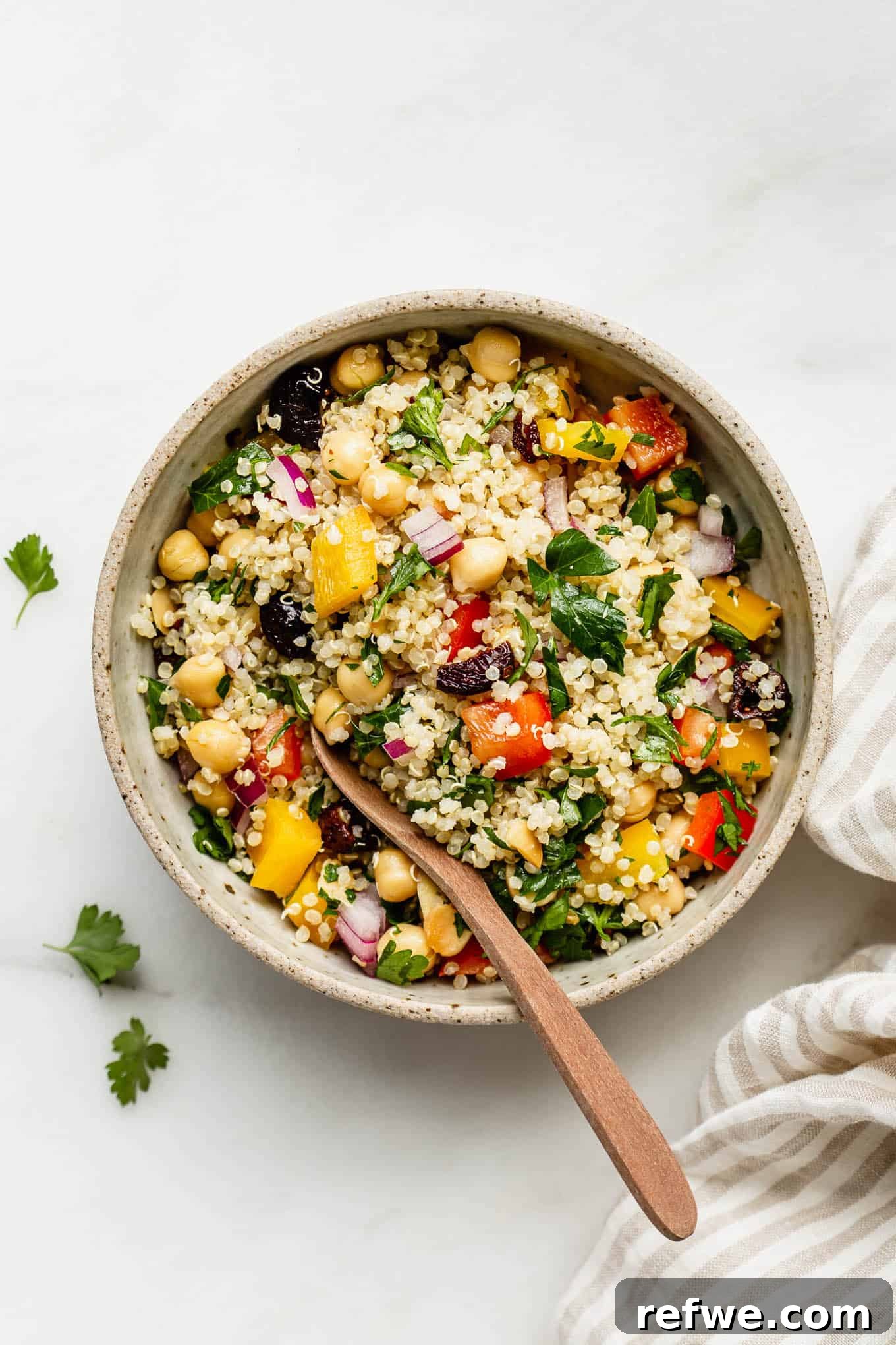 A beautifully arranged bowl of quinoa chickpea salad, accompanied by a striped napkin on the side, ready to be served