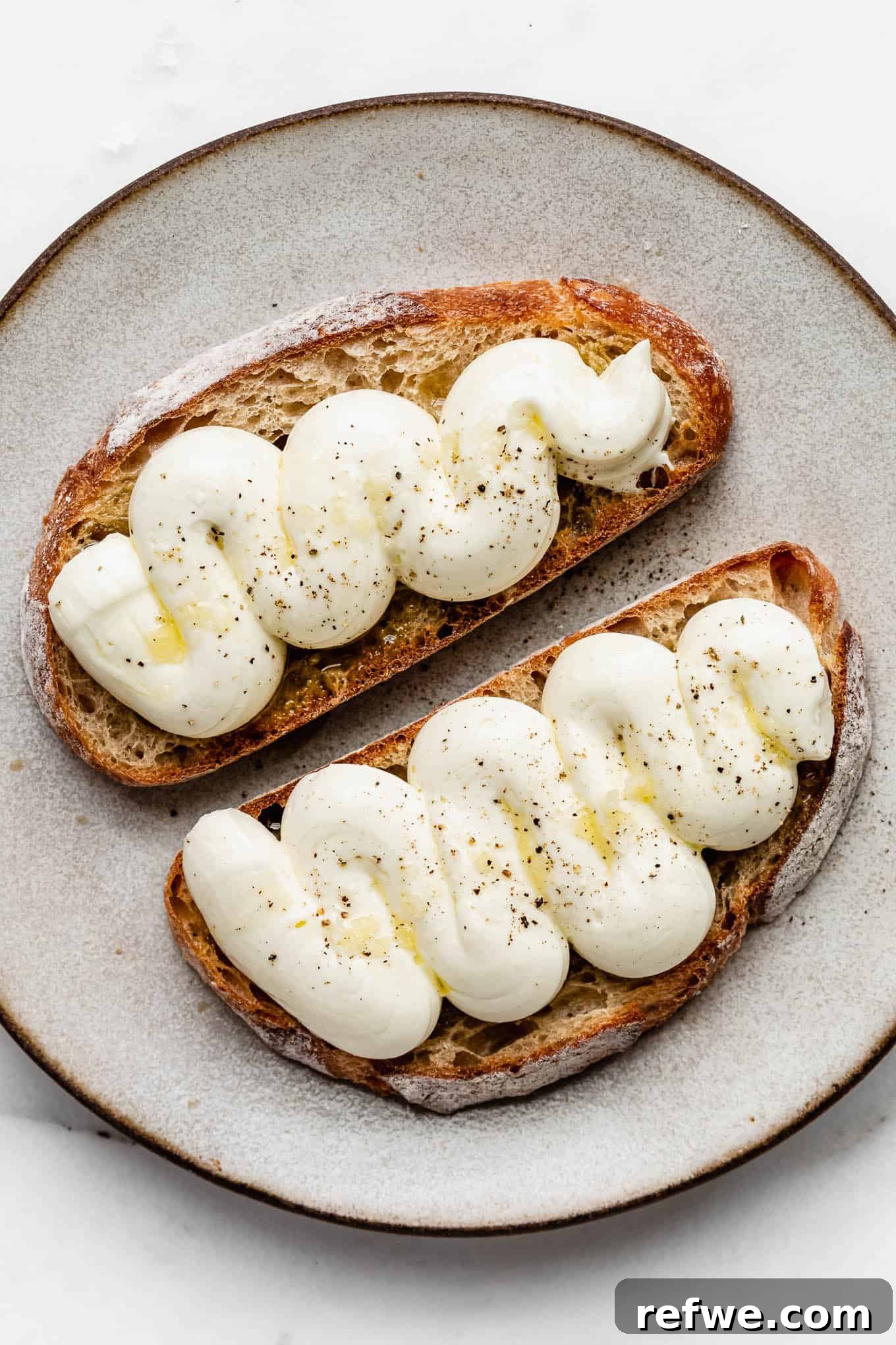 Pillowy Ricotta Toast 2 Two slices of whipped ricotta toast, garnished with olive oil and black pepper, ready for a delicious breakfast.