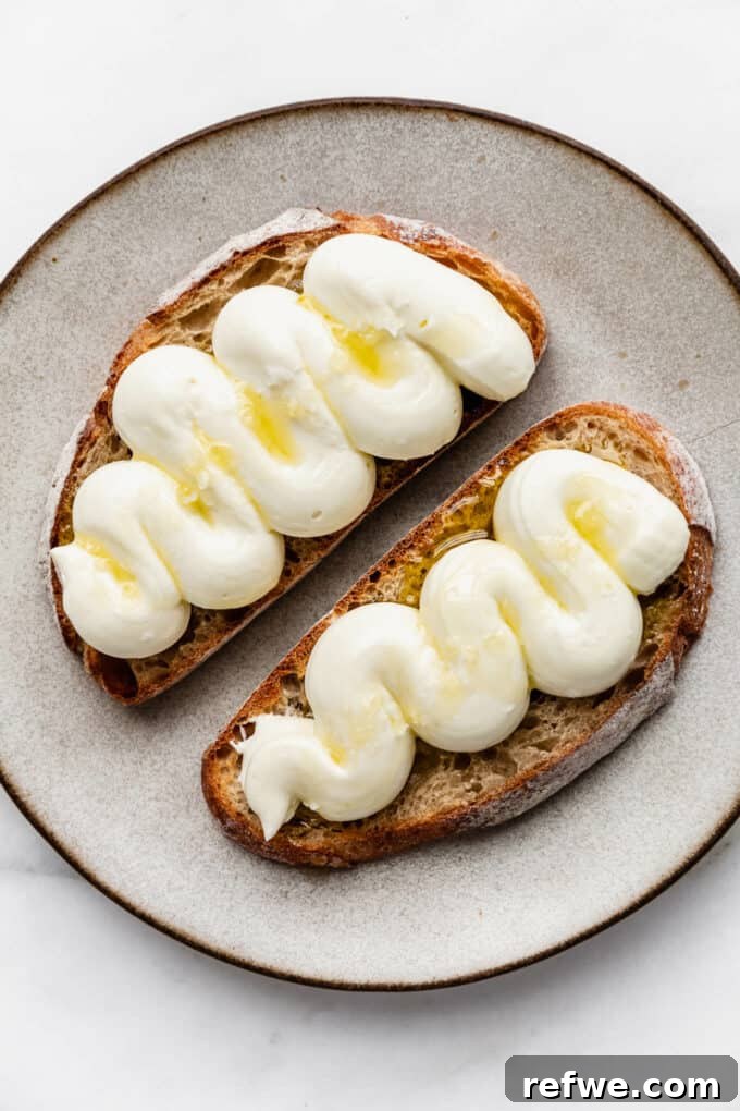 Pillowy Ricotta Toast 6 A close-up of a single slice of sourdough toast topped with whipped ricotta and a delicate olive oil drizzle.