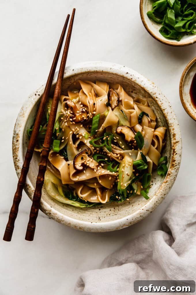 Wok-Tossed Ho Fun 11 A beautifully presented bowl of Ho Fun Noodles on a elegant marble board, garnished with green onions and sesame seeds, ready to be enjoyed.