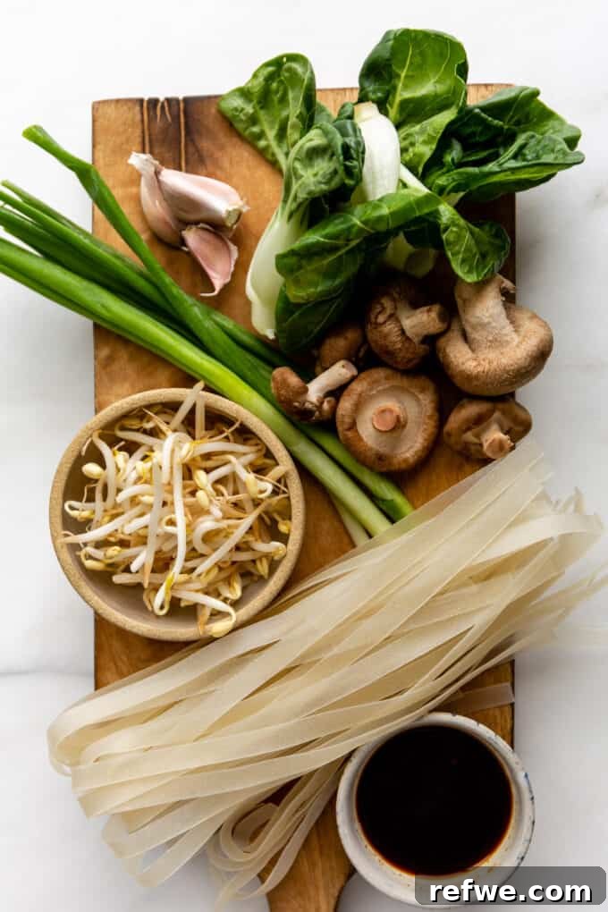 Wok-Tossed Ho Fun 3 A colorful array of ingredients laid out, including wide rice noodles, green onions, shiitake mushrooms, bok choy, garlic, and bean sprouts, ready for a delicious Ho Fun stir-fry.