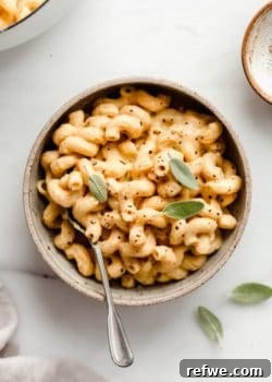 A ceramic bowl filled with butternut squash mac and cheese topped with sage leaves