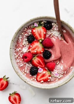 A strawberry smoothie bowl topped with fresh strawberries and shredded coconut, showcasing a delectable and healthy breakfast or snack option.
