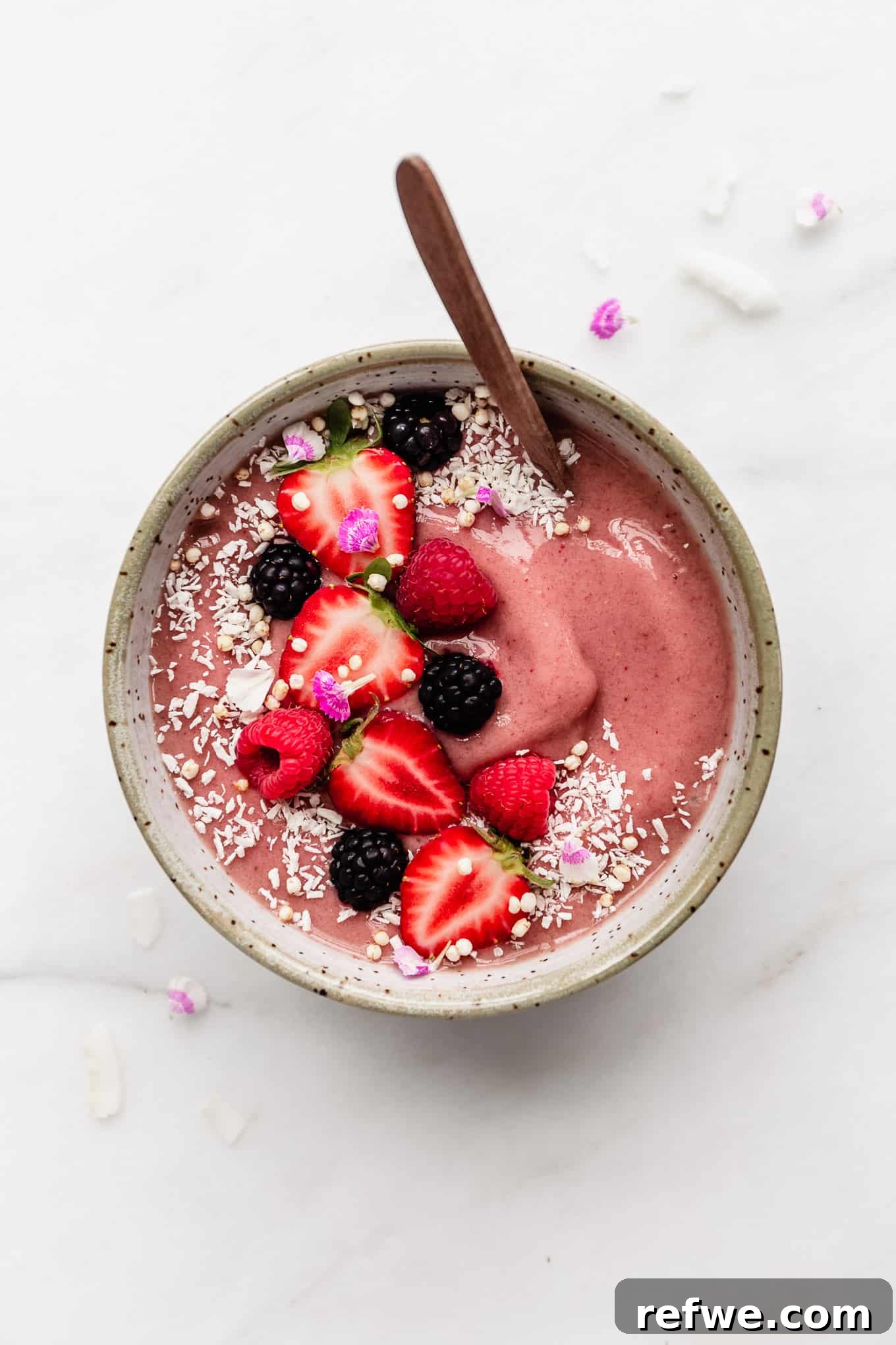 Strawberry Bliss Bowl 7 A close-up of a vibrant strawberry smoothie bowl, beautifully topped with an assortment of fresh berries including whole strawberries and blueberries, showcasing its inviting appeal.