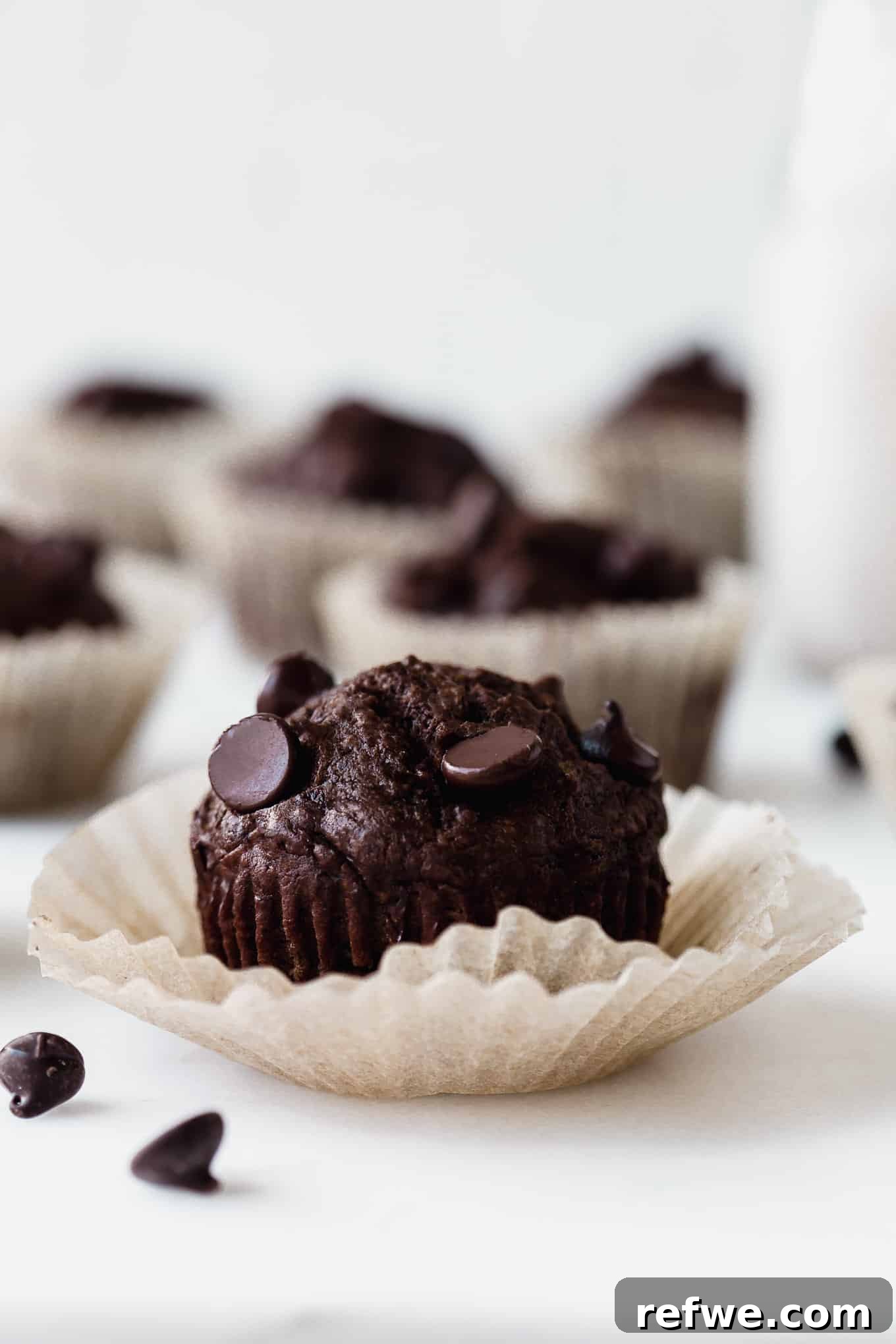 Wholesome Cocoa Zucchini Muffins 12 A single perfectly baked chocolate zucchini muffin, showcasing its moist interior and rich chocolate chips, resting in a paper liner.