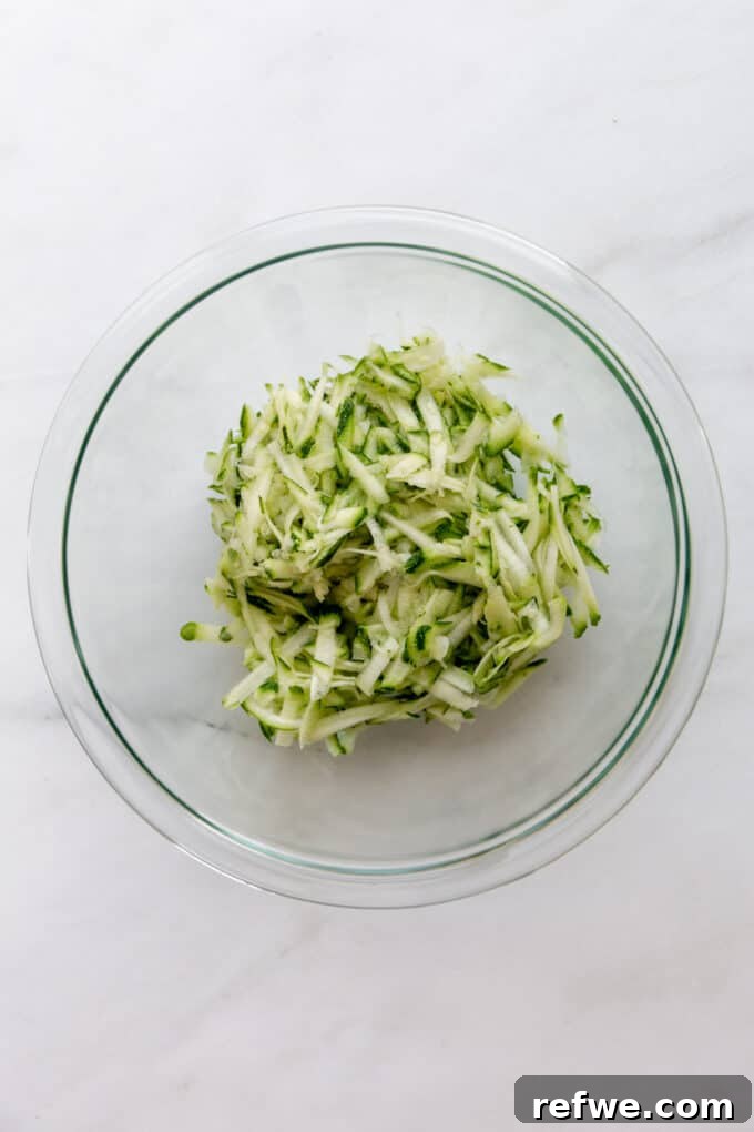Wholesome Cocoa Zucchini Muffins 4 Freshly shredded zucchini in a clear bowl, ready for mixing into the muffin batter.