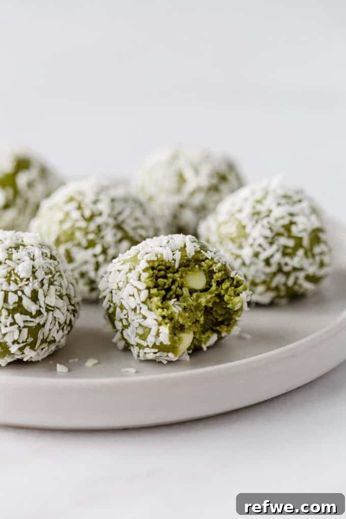 Zen Matcha Fuel Bites 2 matcha balls coated in coconut on a white plate, showcasing their vibrant green color and enticing texture