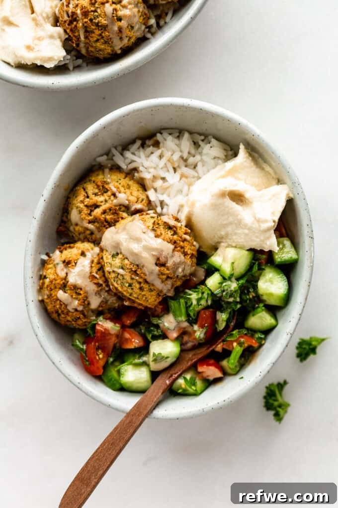 Quick Oven-Baked Falafel Bowls 11 A beautifully arranged falafel bowl with Israeli salad, creamy hummus, and a drizzle of tahini