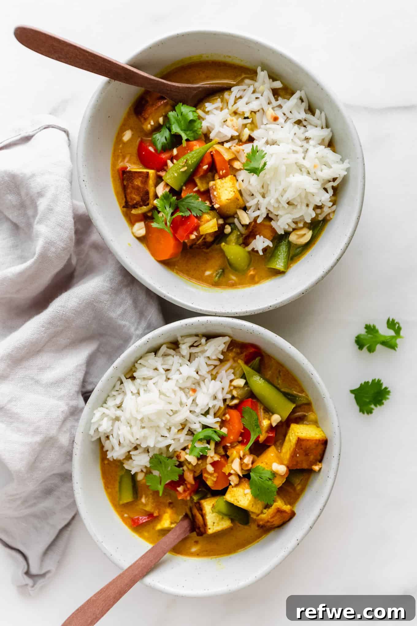 Quick and Creamy Thai Massaman 2 Two bowls of vibrant vegetarian and tofu Massaman curry, served with fluffy white rice and garnished with crushed peanuts.