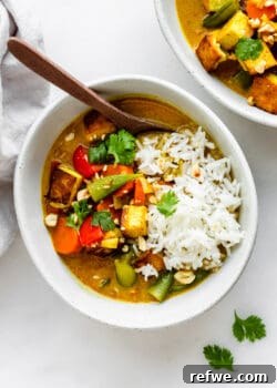 A bowl of massaman curry with rice and peanuts, ready to eat.