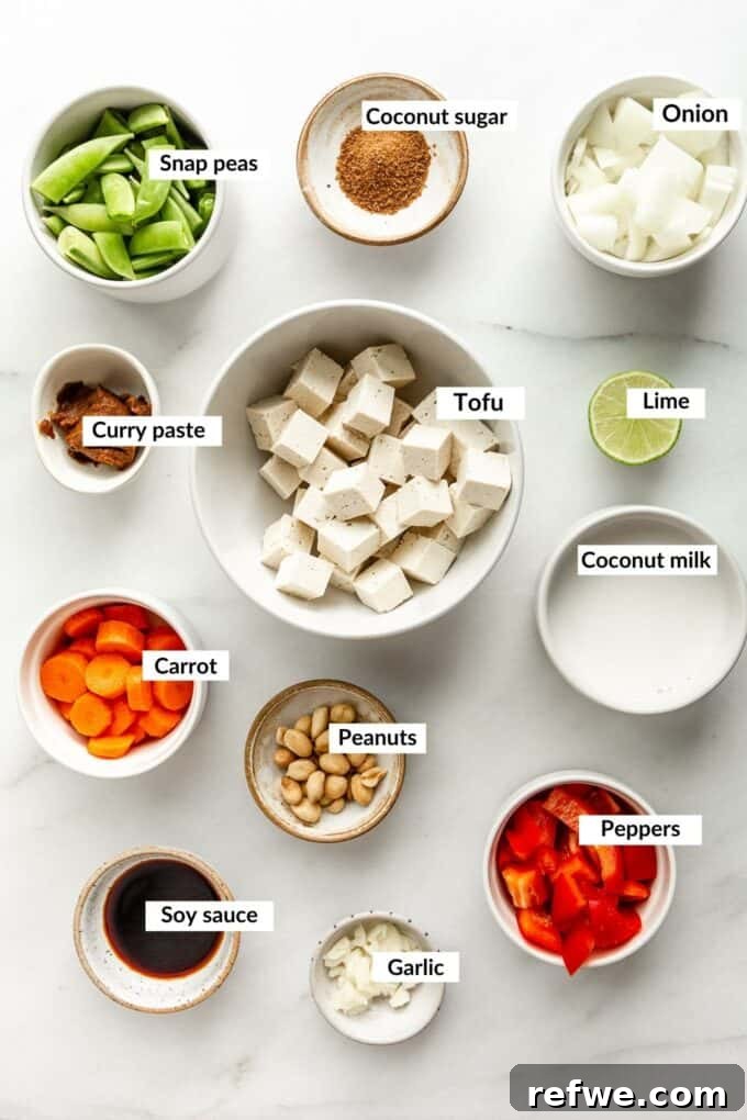 Quick and Creamy Thai Massaman 3 A collection of fresh ingredients laid out, including tofu, onions, garlic, carrots, bell peppers, snap peas, coconut milk, coconut sugar, tamari, and limes, all ready for making Massaman curry.