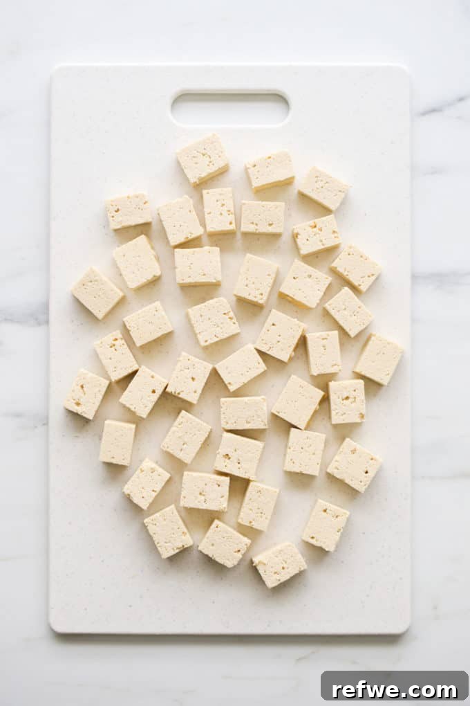 Quick and Creamy Thai Massaman 4 Cubed firm tofu ready to be cooked on a white cutting board.