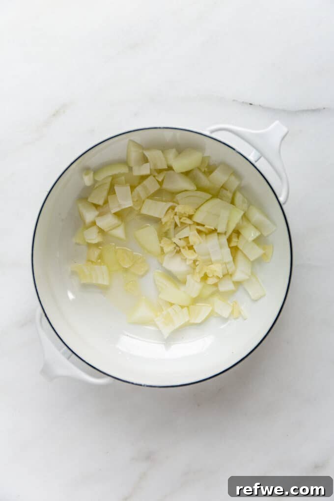 Quick and Creamy Thai Massaman 6 Chopped onions and garlic simmering in oil within a white pot, forming an aromatic base for the curry.