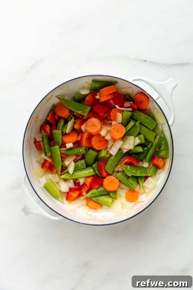 Quick and Creamy Thai Massaman 7 A mix of colorful vegetables, including carrots and bell peppers, being sautéed in a white pot, ready for the curry base.