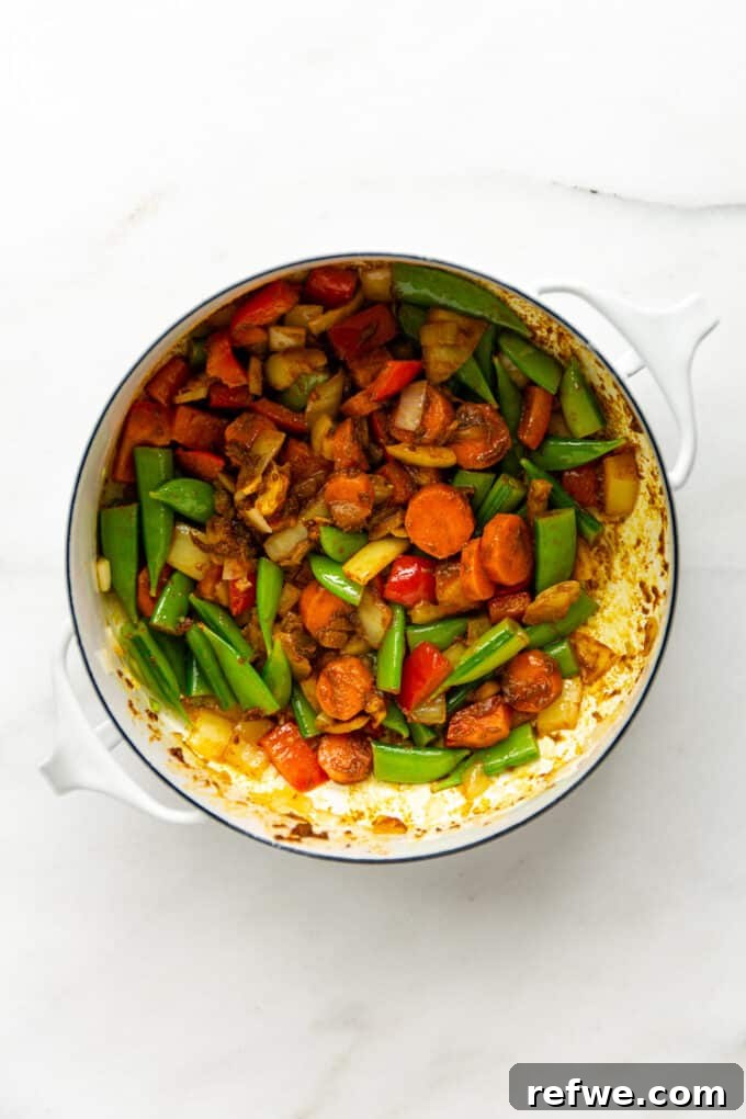 Quick and Creamy Thai Massaman 8 Sautéed vegetables mixed with fragrant Massaman curry paste in a white pot, infusing with rich flavor.